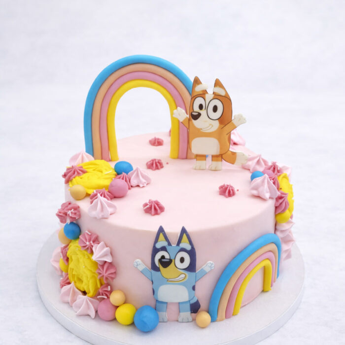 tort Bluey dla dzieci w pastelowym różu z tęczowymi dekoracjami i figurkami