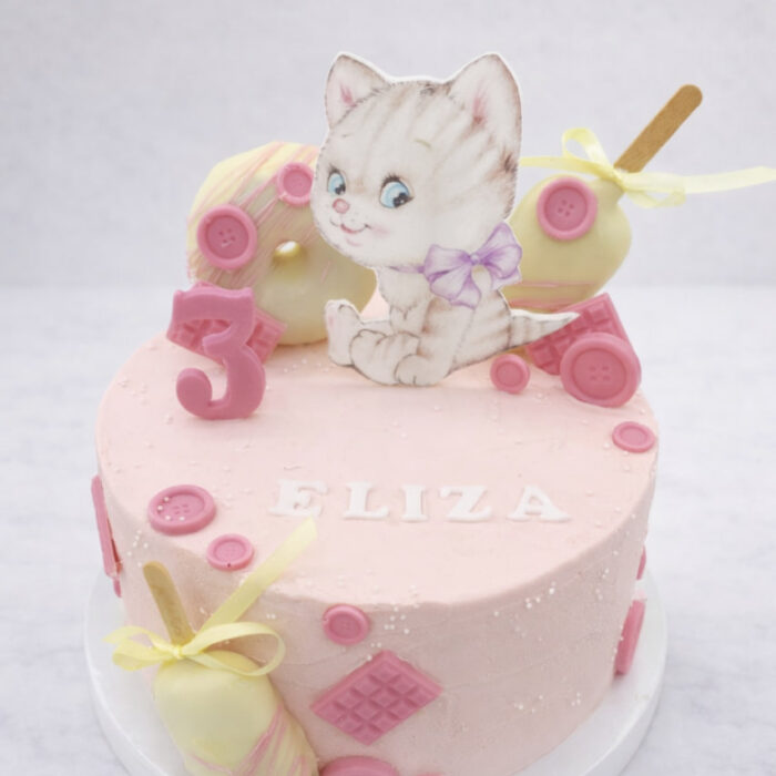 tort z kotkiem dla dzieci w pastelowym różowym kolorze z cukrowymi guzikami